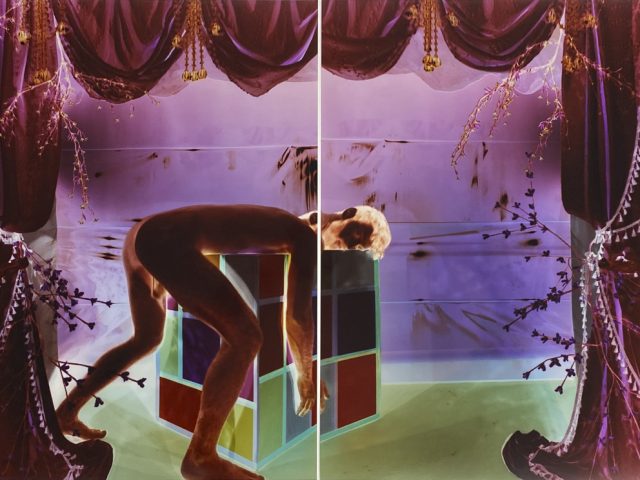 Analog pinhole photograph, diptych, of a nude man bent over a geometric cube in a surreal, theatrical scene of glowing purple drapes and green light.