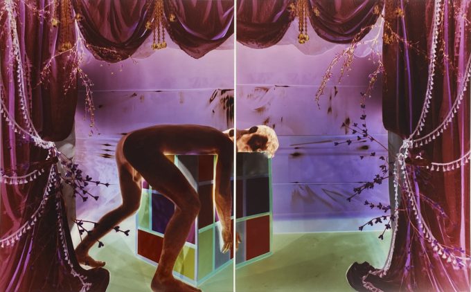 Analog pinhole photograph, diptych, of a nude man bent over a geometric cube in a surreal, theatrical scene of glowing purple drapes and green light.