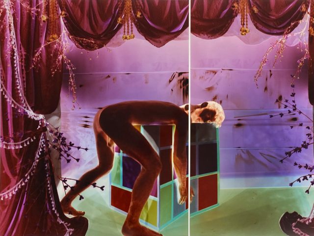 Analog pinhole photograph, diptych, of a nude man bent over a geometric cube in a surreal, theatrical scene of glowing purple drapes and green light.