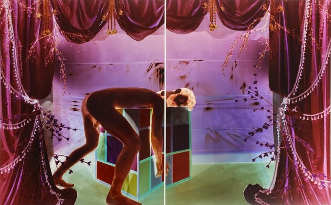 Analog pinhole photograph, diptych, of a nude man bent over a geometric cube in a surreal, theatrical scene of glowing purple drapes and green light.