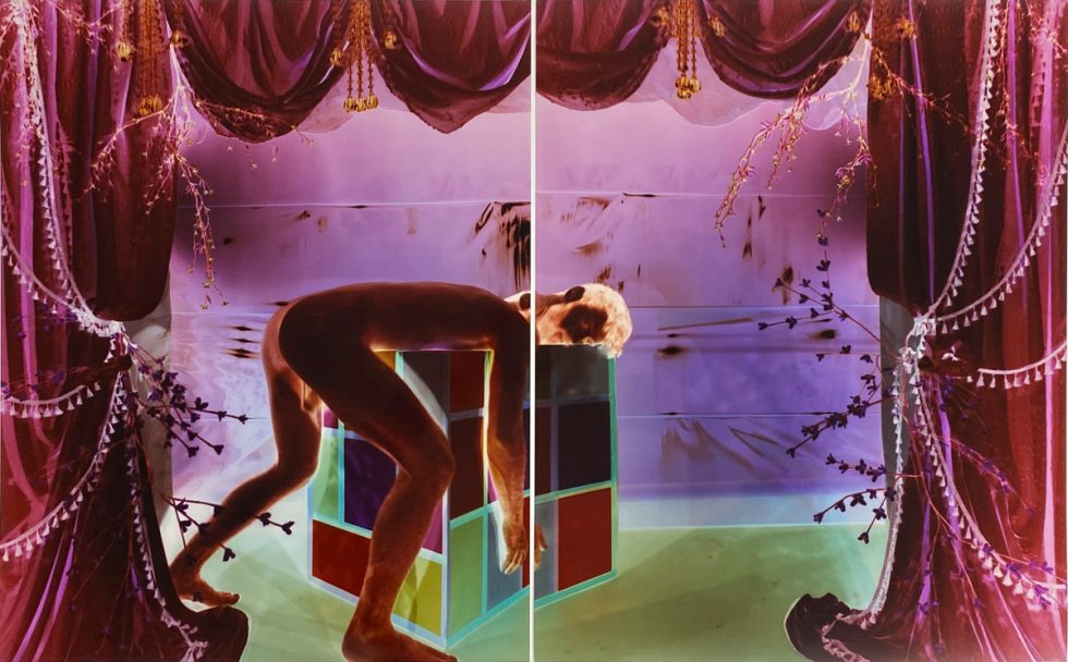 Analog pinhole photograph, diptych, of a nude man bent over a geometric cube in a surreal, theatrical scene of glowing purple drapes and green light.