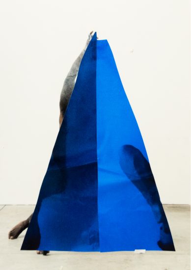 A photograph of a blue triangle in a white gallery or studio setting.