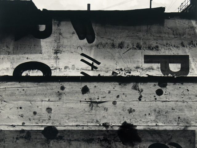 A black and white photograph of a sign with a few letters on it