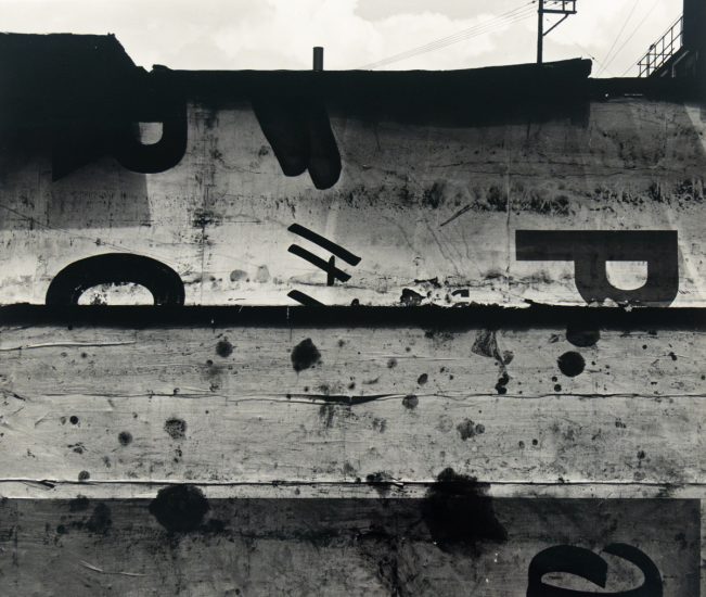 A black and white photograph of a sign with a few letters on it