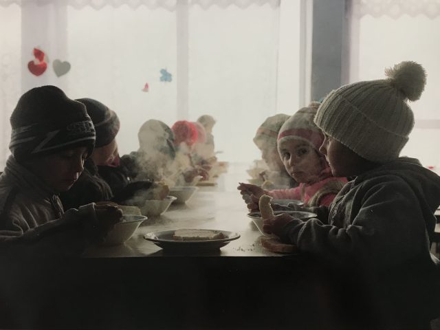 A color photograph of a group of small children sitting around a table.