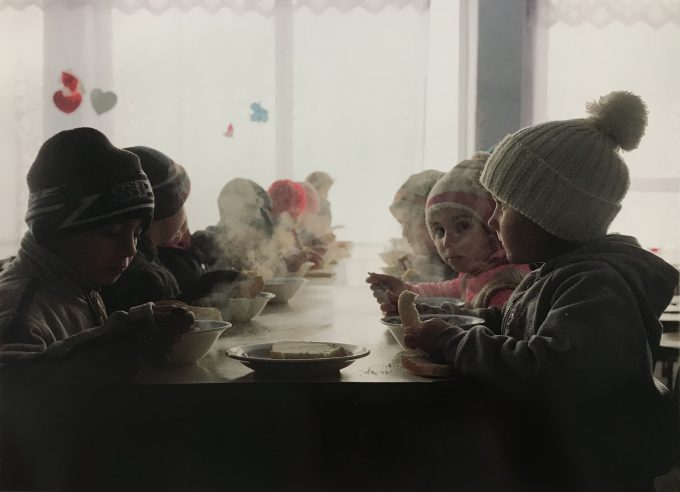 A color photograph of a group of small children sitting around a table.