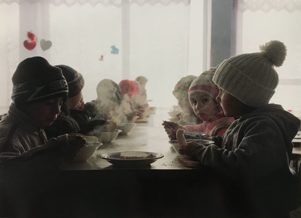 A color photograph of a group of small children sitting around a table.