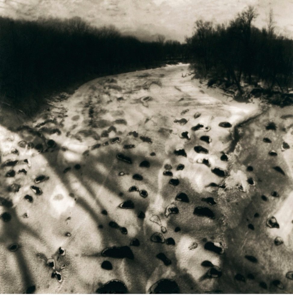 A black and white photograph of a snowy landscape scene.
