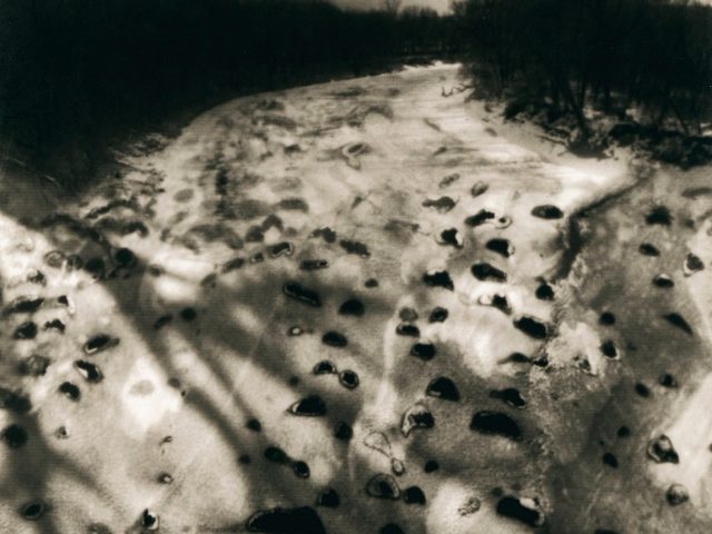 A black and white photograph of a snowy landscape scene.