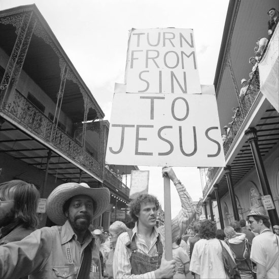 A black and white photograph of a christian protestor at Mardi Gras.