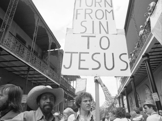 A black and white photograph of a christian protestor at Mardi Gras.