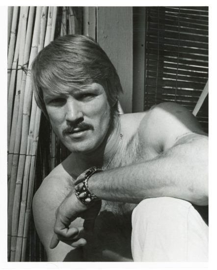 A black and white portrait of a handsome shirtless man.