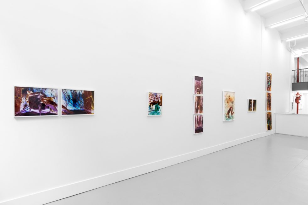 A photograph of a white-walled gallery space with colorful photographs on display.