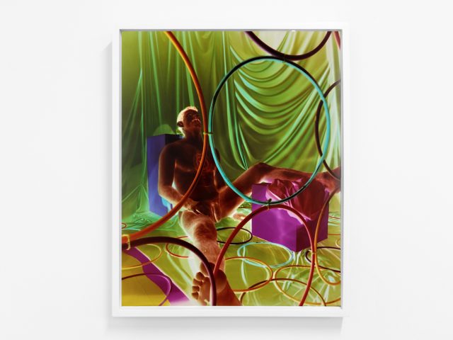 A photograph of a white-walled gallery space with colorful photographs on display.