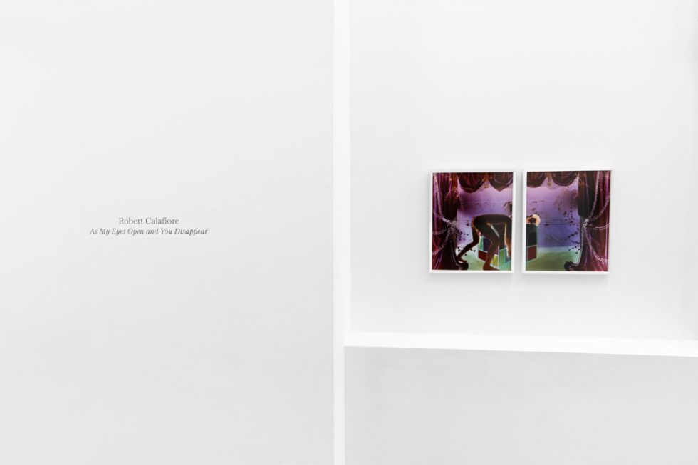 A photograph of a white-walled gallery space with colorful photographs on display.