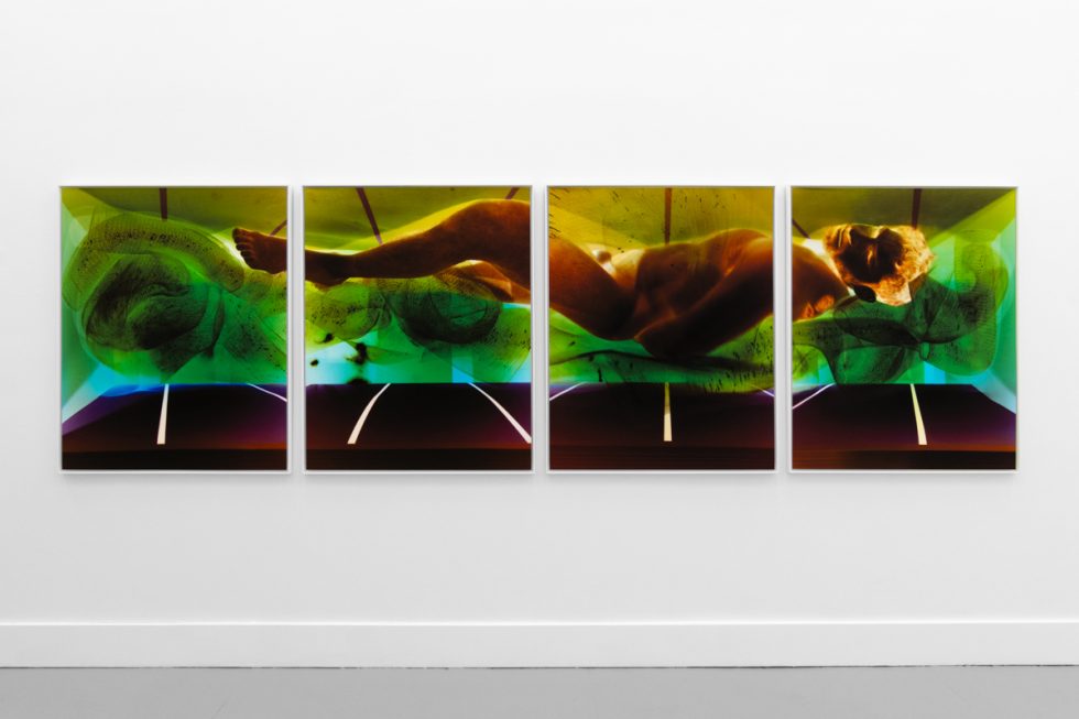 A photograph of a white-walled gallery space with colorful photographs on display.