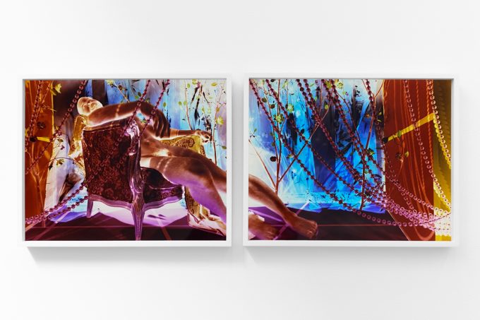 A photograph of a white-walled gallery space with colorful photographs on display.