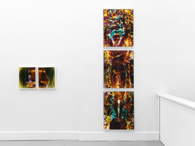 A photograph of a white-walled gallery space with colorful photographs on display.