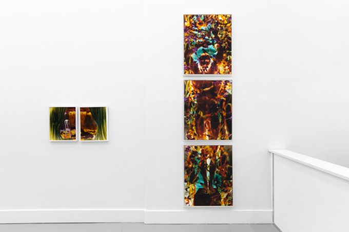 A photograph of a white-walled gallery space with colorful photographs on display.