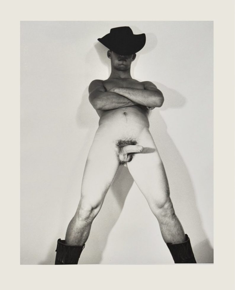 A black and white nude photograph of a man in a cowboy hat.