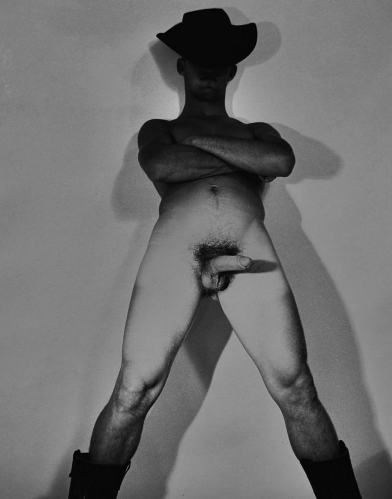 A black and white nude photograph of a man in a cowboy hat.