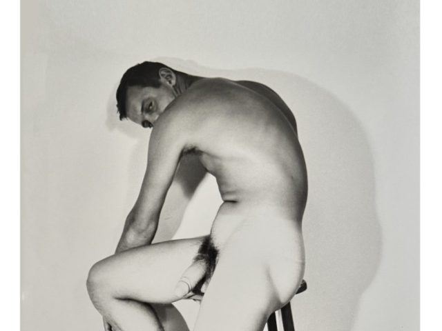 A black and white nude photograph of a man in a cowboy hat.