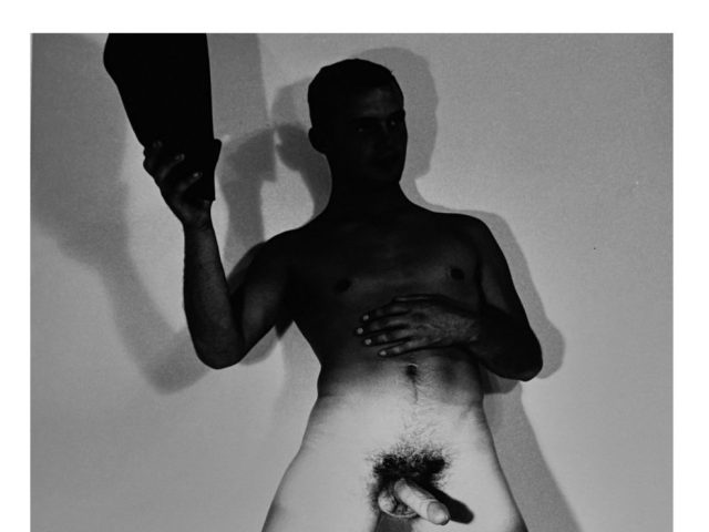 A black and white nude photograph of a man in a cowboy hat.