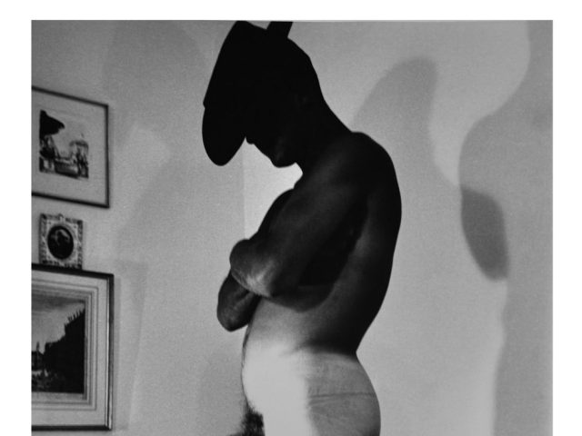 A black and white nude photograph of a man in a cowboy hat.