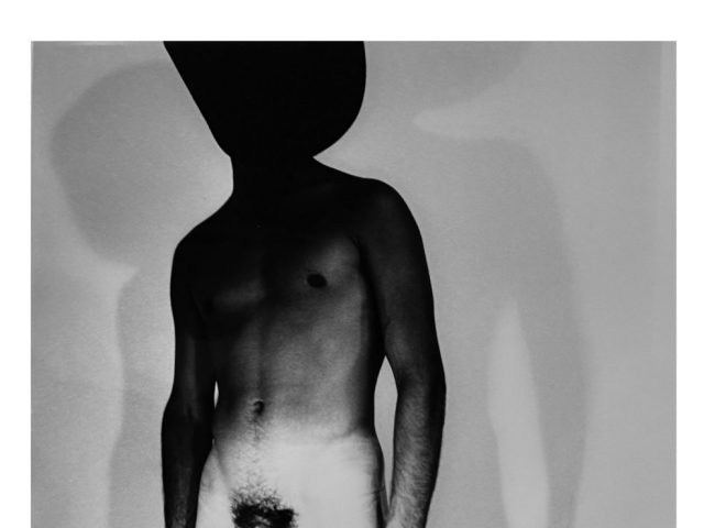 A black and white nude photograph of a man in a cowboy hat.