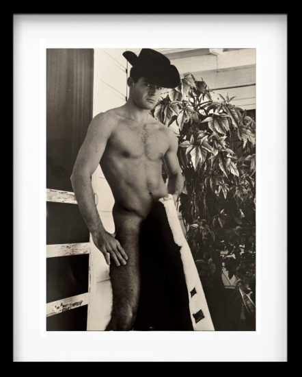 A black and white photograph of a shirtless man holding a jacket.