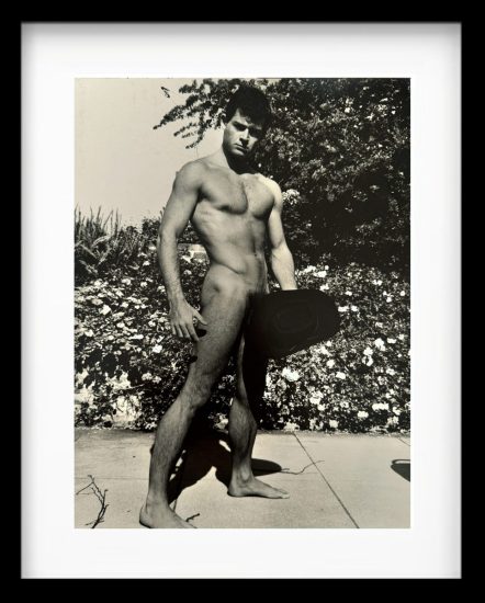 A black and white photograph of a nude man standing outside.