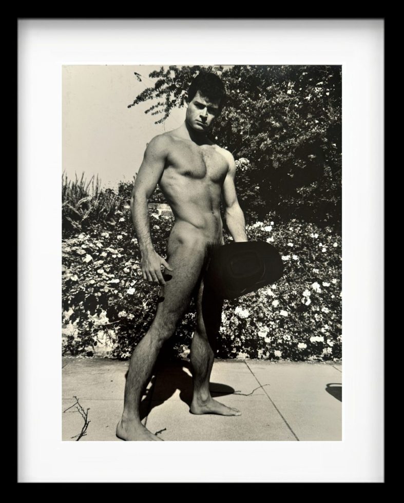 A black and white photograph of a nude man standing outside.
