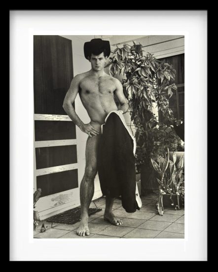 A black and white photograph of a handsome shirtless man standing.