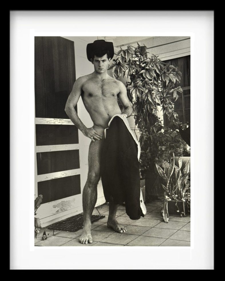 A black and white photograph of a handsome shirtless man standing.
