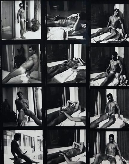 A black and white photograph of a nude man sitting outside in the sun.