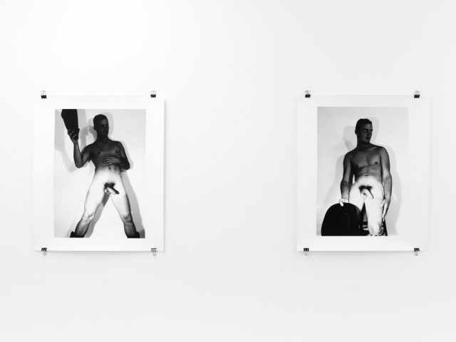 An installation photograph of black and white photography in a white-walled gallery space.