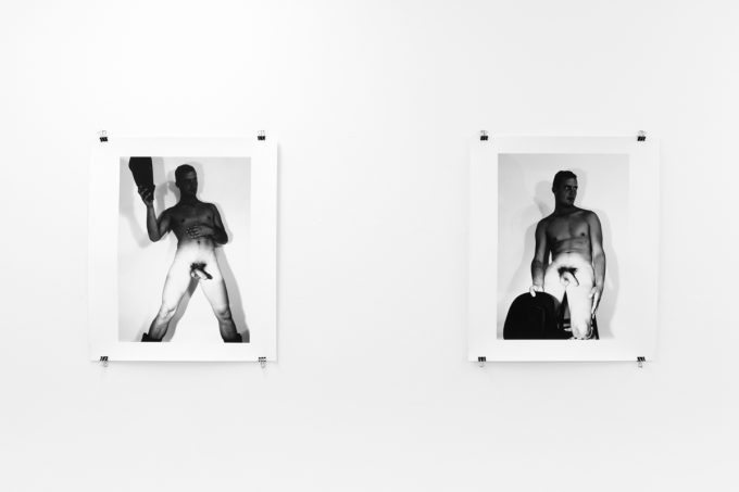 An installation photograph of black and white photography in a white-walled gallery space.