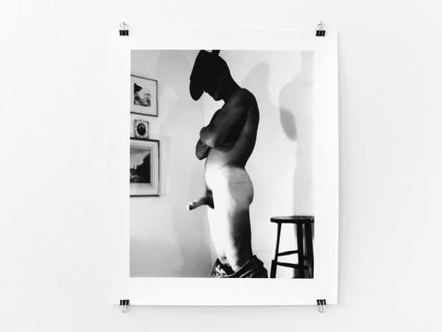 An installation photograph of black and white photography in a white-walled gallery space.