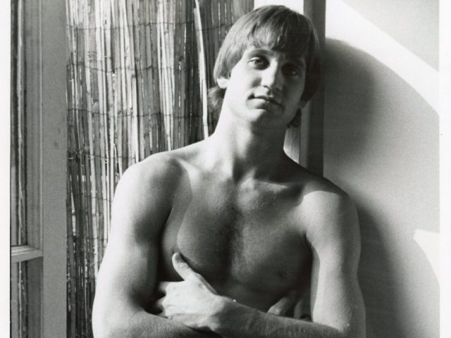 A black and white photograph of a nude man with an erection.