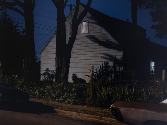 A photograph of a house lit by a streetlight at night.