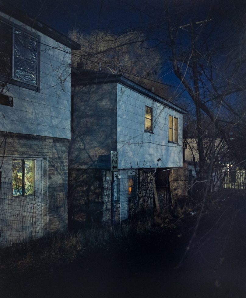 A blue toned image of a collection of suburban houses at night.
