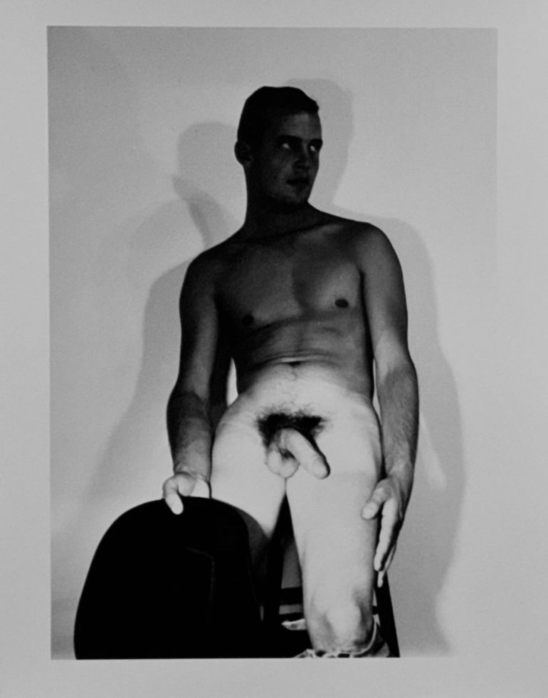 A black and white nude photograph of a man in a cowboy hat.