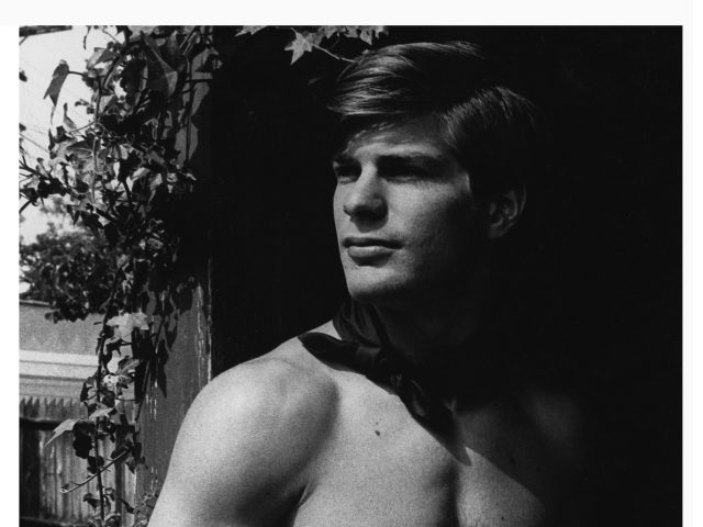 A black and white photograph of a handsome shirtless man.
