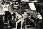A black and white photograph of a gay porn set with camera men and professional lighting.