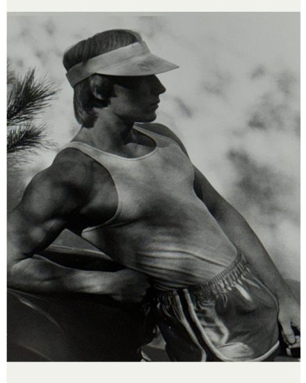 A black and white photograph of a man in gym clothes and a visor.