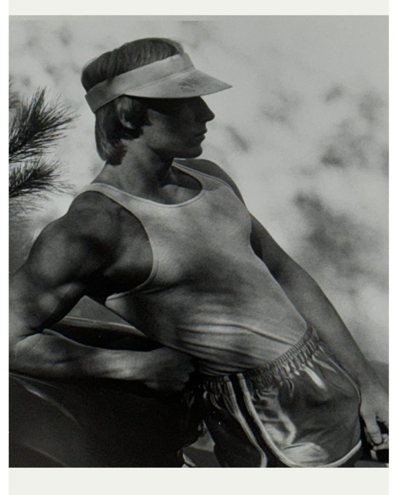 A black and white photograph of a man in gym clothes and a visor.