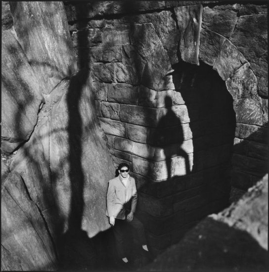 A black and white photograph of a man standing in a park.