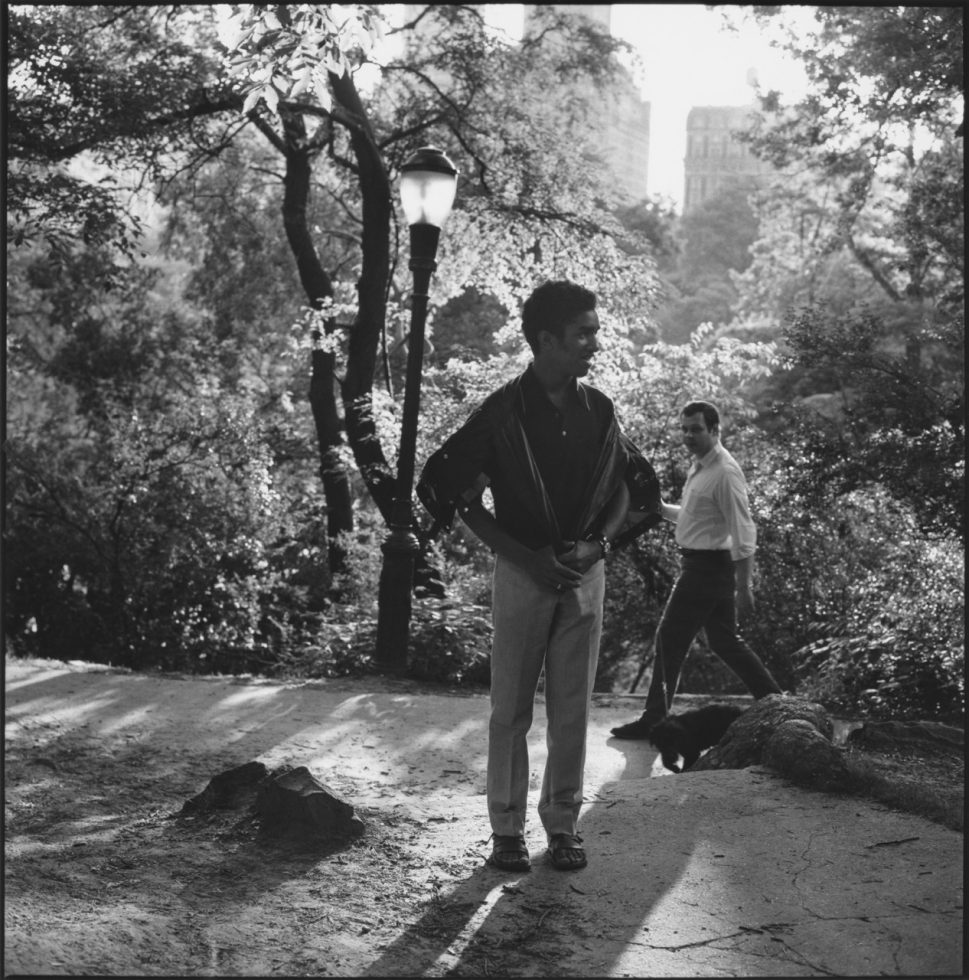 A black and white photograph of a man standing in a park.
