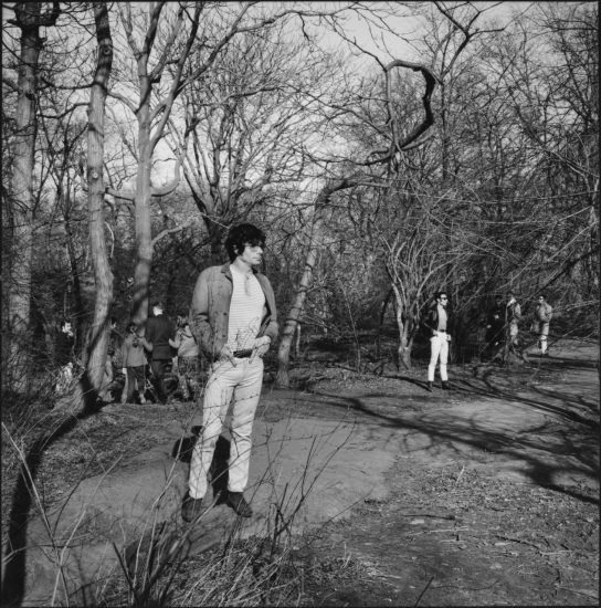 A black and white photograph of a young man in a city park.