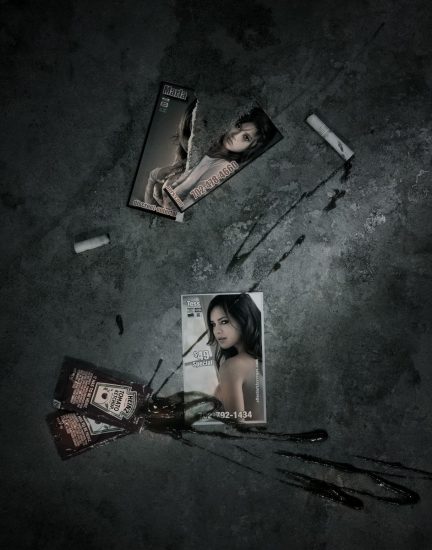 A photograph of two escort cards with splattered ketchup on a concrete sidewalk.